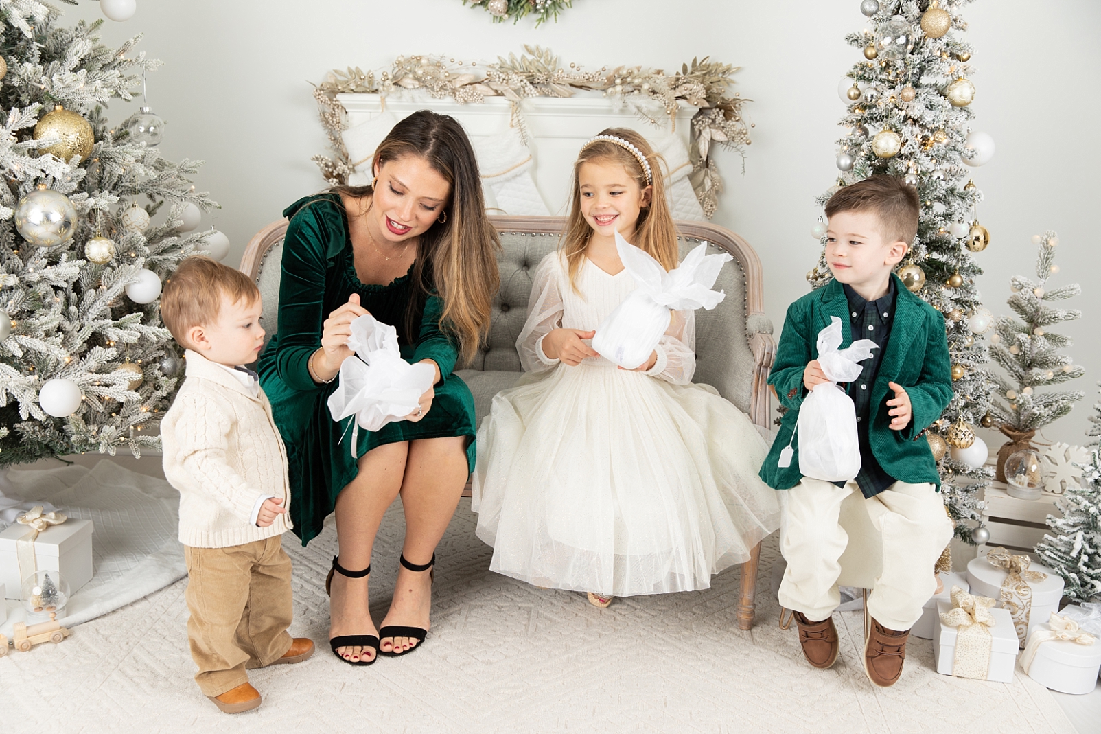 A mom opening gifts wrapped in tissue paper with 3 children for Christmas Sessions Maryland with Rebecca Leigh Photography