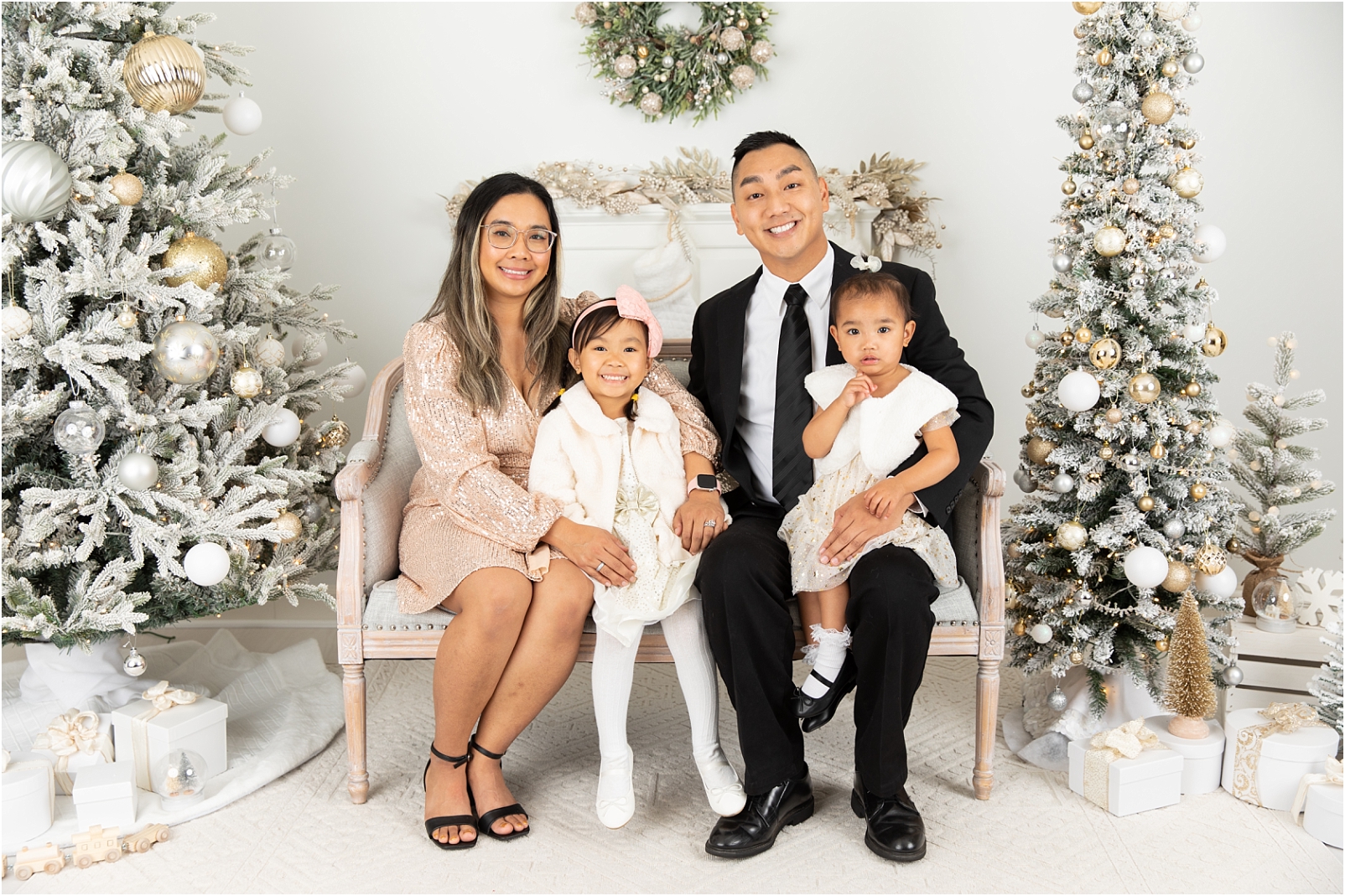 Family of 4 sitting on a loveseat wearing semi-formal attire for Christmas Sessions Maryland with Rebecca Leigh Photography