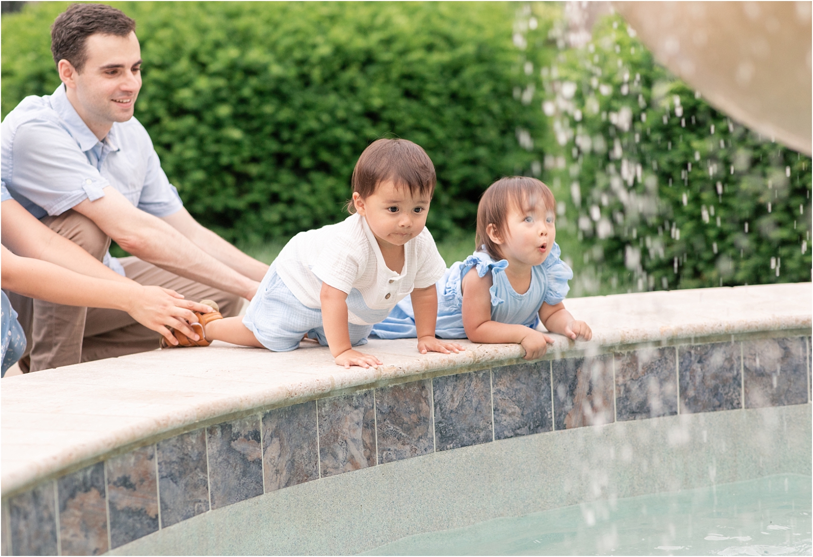 How to Prepare Toddlers for a Photo Session - Rebecca Leigh Photography - Twin boy and girl are looking at a large fountain of water while the parents are holding onto them