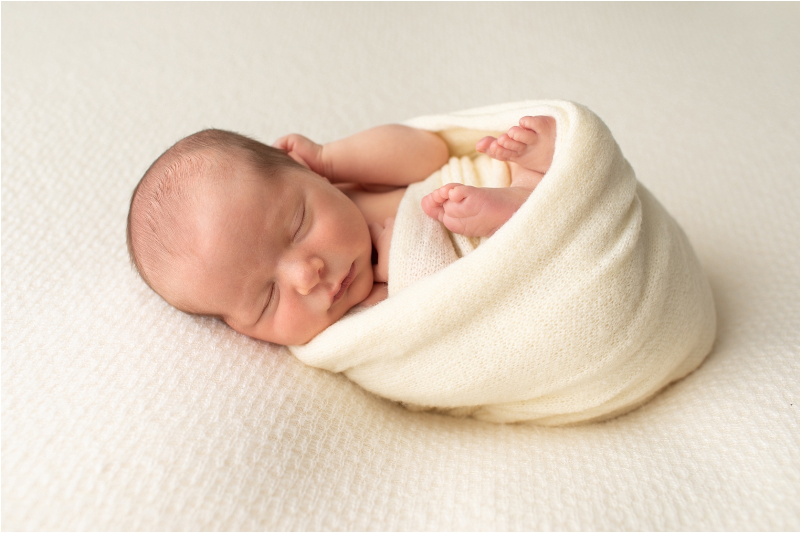 Newborn baby boy wrapped in a cream color swaddle sleeping - When Should we Book a Newborn Photo Session? 3 Reasons to Book Early with Rebecca Leigh Photography
