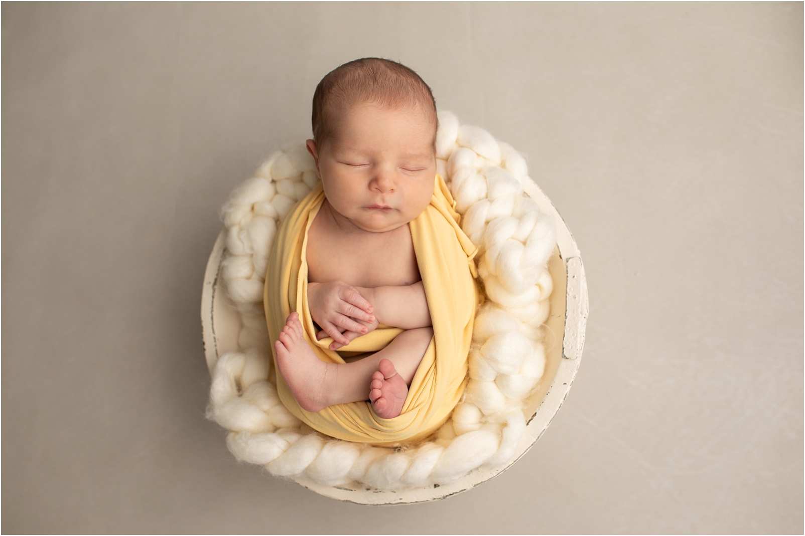 Newborn baby boy wrapped in a yellow swaddle sleeping - When Should we Book a Newborn Photo Session? 3 Reasons to Book Early with Rebecca Leigh Photography
