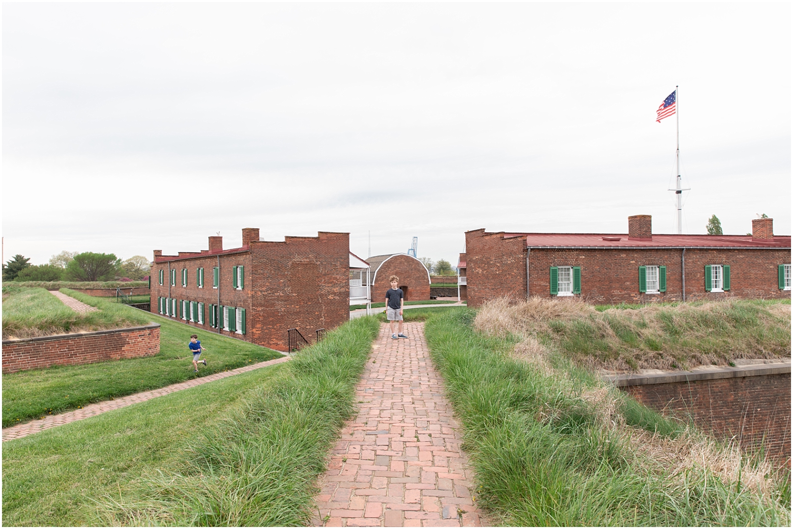 A red brick pathway with a boy standing on it at Fort McHenry for family activities in Baltimore, Maryland