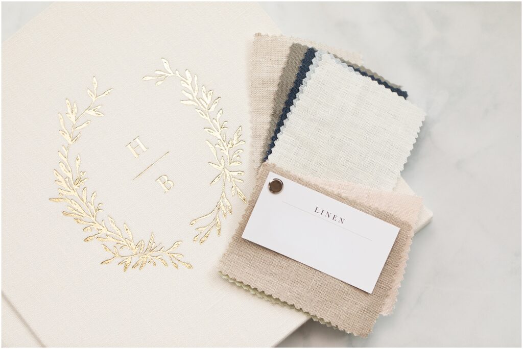 Cream color linen heirloom albums | Newborn Photos with gold wreath and letters embossing and linen fabric samples for Rebecca Leigh Photography