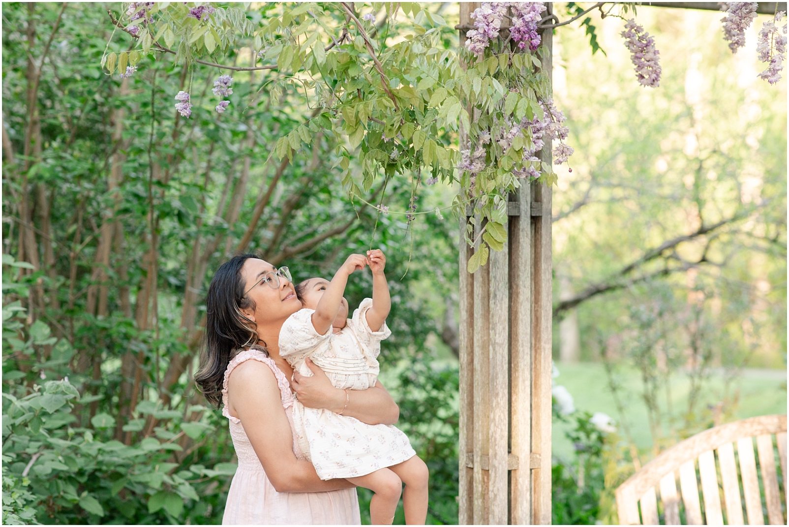Mom lifting her daughter to look at a floral vine