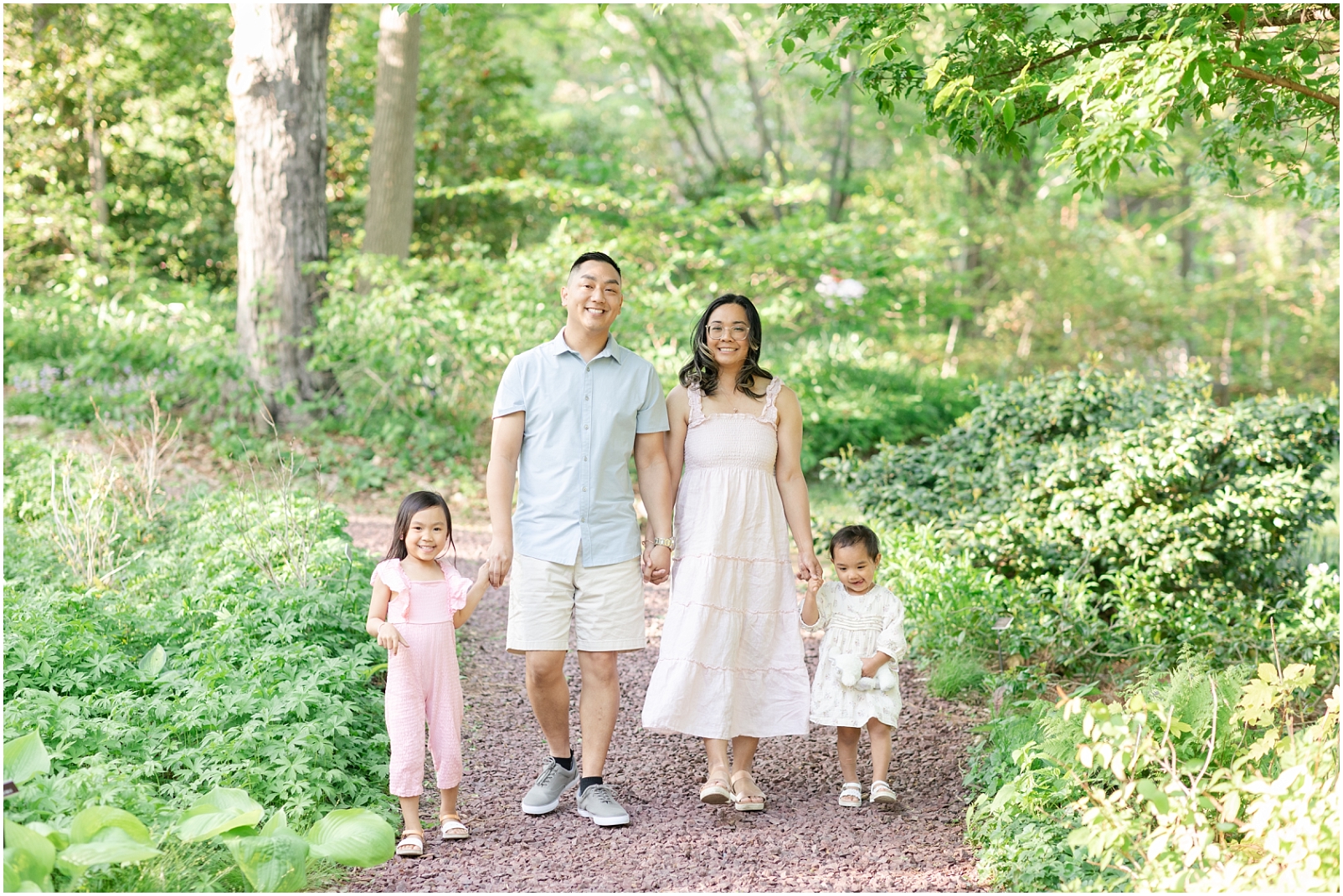 Family of 4 walking on a pathway through a garden