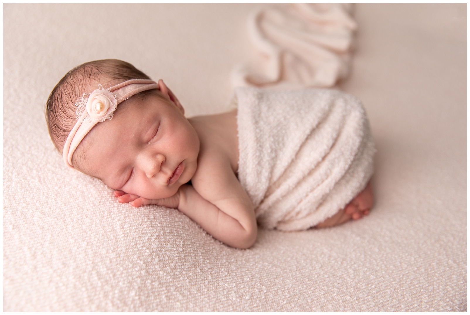 5 Tips to Prepare for a Newborn Photo session with a newborn girl wrapped in light pink and wearing a floral headband while sleeping